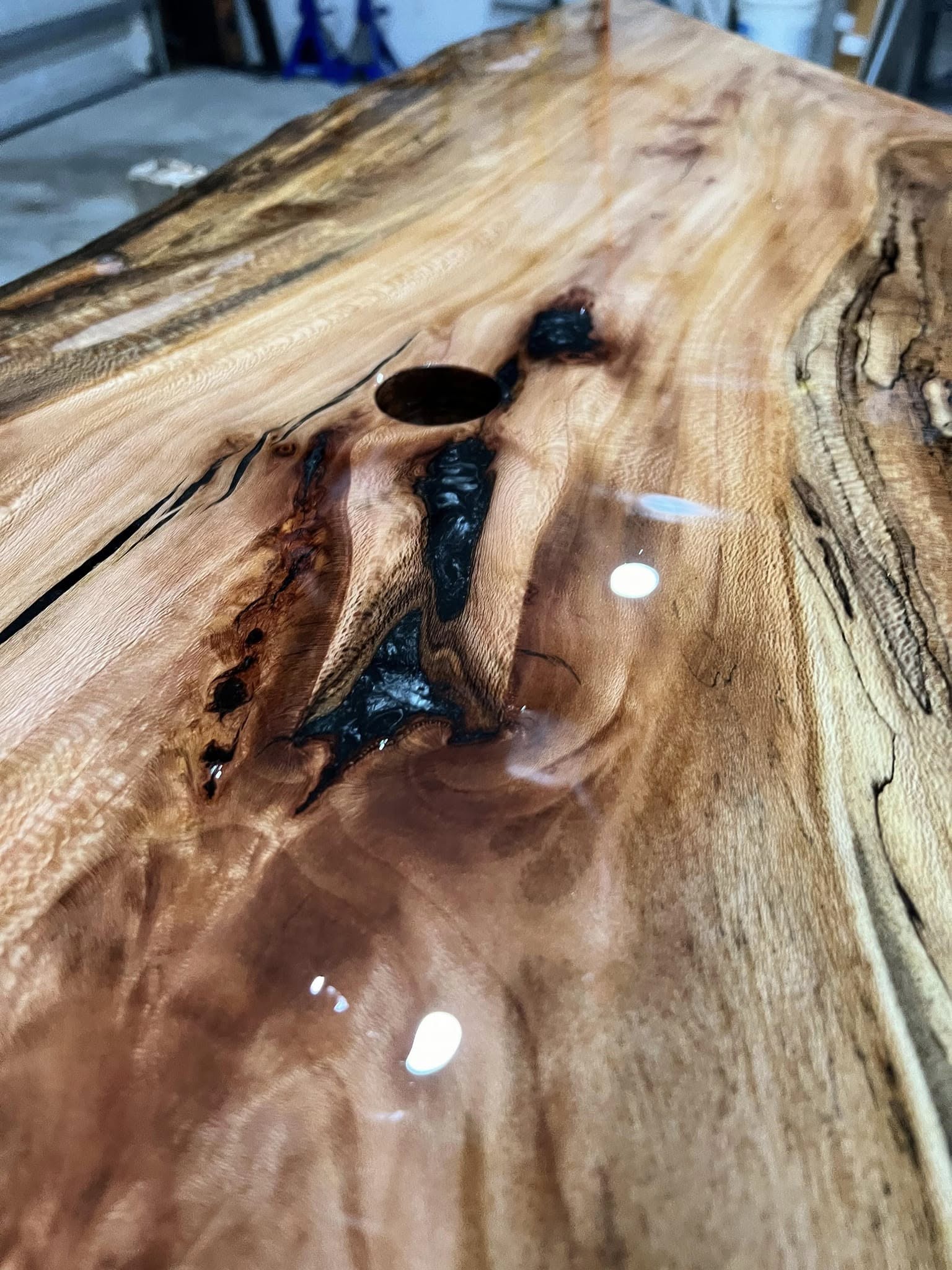 Close-up of finished live-edge slab with black epoxy resin filling natural cracks